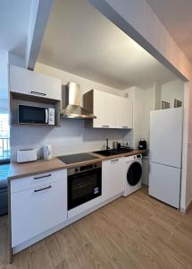a kitchen with white cabinets and a white refrigerator at Superbe appartement neuf - 5min beach walk in Nice