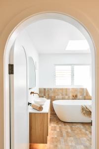 a bathroom with a white tub and a sink at Entre Palmas Ballina in Ballina