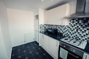 a kitchen with black and white tile on the wall at Comfy Home-Wood Green in London