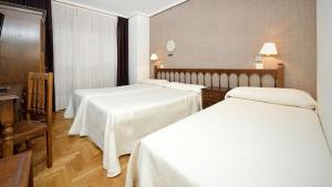 a hotel room with two beds with white sheets at Hotel El Molinón in Cangas del Narcea