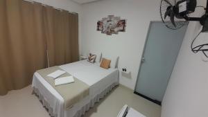 um quarto branco com uma cama e um espelho em Pousada Jeitim Mineiro em Capitólio