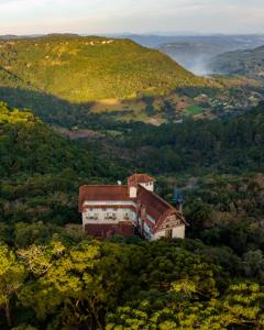 una casa en una colina en medio de un bosque en Villa Bella Hotel & SPA Gramado, en Gramado