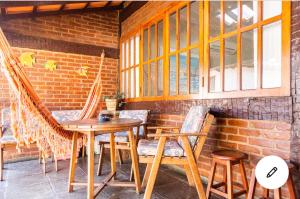 un patio con una mesa de madera, sillas y una pared de ladrillo en Geribá Apart Hotel Internacional Buzios, en Búzios