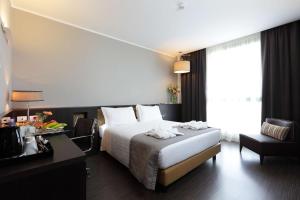 um quarto de hotel com uma cama, uma secretária e uma janela em Best Western Premier CHC Airport em Gênova