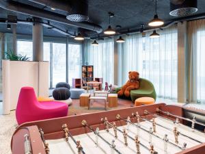 una habitación con un osito de peluche sentado en una silla junto a una mesa de billar en ibis Styles Bern City, en Berna