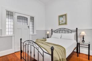 a bedroom with a bed and two tables with lamps at Noir Cottage Glenelg North in Glenelg