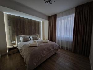 a bedroom with a large bed with two towels on it at Dendrarium Park Apartment Deluxe in Chişinău