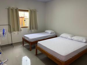 two beds in a room with a window at Casa Ametista in Pirenópolis