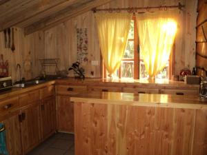 una cocina con armarios de madera y una ventana con cortinas en Cabaña Rustica Patagonia Chilena, en Coñaripe