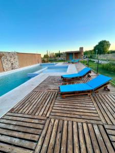 a pool with blue lounge chairs on a wooden deck at Complejo ROSA OLIVA in Albardón