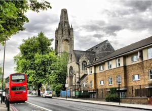 un bus rouge à deux étages garé devant une église dans l'établissement Victorian Building turned Charming Hotel Perfect For Short and Long Term Stay with WiFi, à Londres