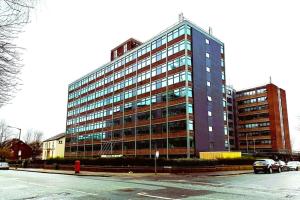a tall building with cars parked in front of it at Fantastic one bedroom apartment near Old Trafford Stadium in Manchester