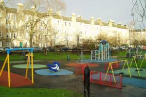 a playground in front of a large building at Charming Hotel with Kitchen & Laundry near Tufnell Park in London