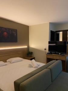 a hotel room with a bed and a flat screen tv at Flat Lake Side cantinho café Lago Paranoá Brasília Df in Brasilia