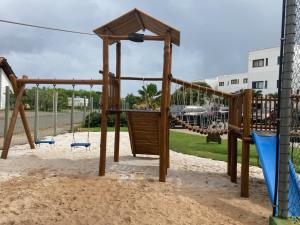 a playground with a swing set in the sand at Apartamento no Complexo Iberostate in Acu da Torre