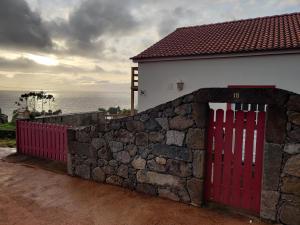 uma porta vermelha numa parede de pedra ao lado de uma casa em Casa da Eira em Calheta