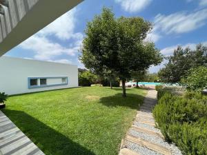 un patio verde con un árbol y una casa blanca en Casa Koya- Luxury house in the countryside 