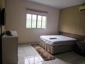 a bedroom with a bed and a window and a rug at Chácara Rio Cachoeira in Antonina