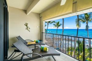 un balcón con 2 sillas, una mesa y el océano en Oceanfront Luxury Condo, en Kailua-Kona