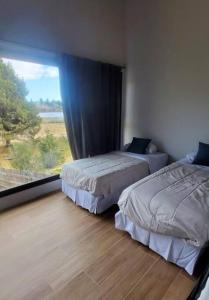 2 camas en una habitación con ventana grande en Paihuen: casa moderna con vista en San Carlos de Bariloche