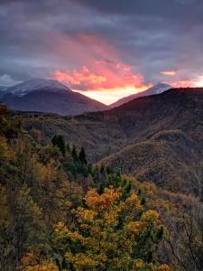 una puesta de sol en las montañas con árboles y una montaña en La Salira 