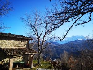 ein Steinhaus mit einem Baum und Bergen im Hintergrund in der Unterkunft La Salira 