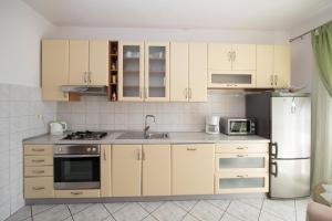 eine Küche mit weißen Schränken, einer Spüle und einem Kühlschrank in der Unterkunft Apartment Brela 16603b in Brela