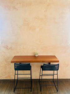 a wooden table with two chairs in front of a wall at Hotelito YUM KAAX in Mérida