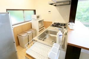 uma pequena cozinha com um lavatório e uma máquina de lavar louça em Y's あたみんち em Atami