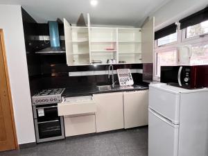 a kitchen with white cabinets and a sink and a refrigerator at Full Studio Near Heathrow Airport & London in Hayes