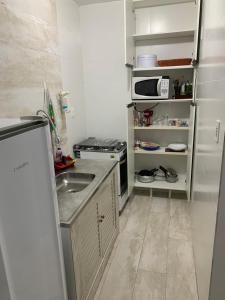 una pequeña cocina con fregadero y microondas en Apartamento - Diária ou Curta Temporada 34, en Salvador