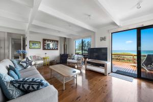 a living room with a couch and a table and a television at Surfside on Mollymook Beach in Mollymook
