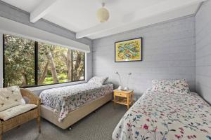 a bedroom with two beds and a window at Surfside on Mollymook Beach in Mollymook