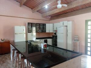 una cucina con elettrodomestici bianchi e piano di lavoro nero di Chácara Biritiba Mirim, Bairro Nirvana - Mogi das Cruzes a Biritiba-Mirim
