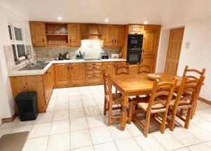uma cozinha com armários de madeira e uma mesa e cadeiras de madeira em Main Street Cottage, Ballintoy em Ballintoy