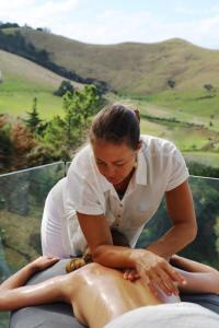 a woman is waxing a persons body on a bed at Omana in Rocky Bay
