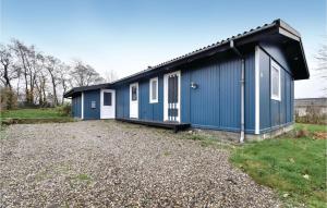 a blue building with white doors and a gravel yard at Four-Bedroom Holiday Home In Brenderup Fyn in Skovs-Højrup