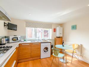 a kitchen with a washing machine and a table at Mermaid Cottage in Whitby