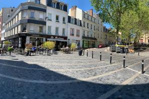 una calle adoquinada con mesas, sillas y edificios en Au cœur du Quartier St Vincent de Paul, Le Havre en Le Havre