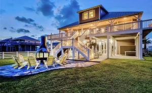 een groot huis met schommelstoelen op het gazon bij Sunrise, Sunburn, Sunset, Repeat home in Stingaree