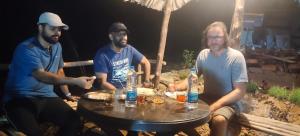 Eine Gruppe von drei Männern, die um einen Tisch sitzen. in der Unterkunft PONMUDI DALE. HOMESTAY in Kallar-Bridge