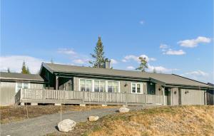 una casa verde con porche y valla en Stunning Home In Sjusjen With House A Mountain View en Sjusjøen