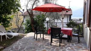 een tafel en stoelen met een rode parasol op een patio bij Appartement in Cassone Di Malcesine mit Garten in Malcesine