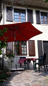 een rode paraplu naast een tafel en een bank bij Appartement in Cassone Di Malcesine mit Garten in Malcesine