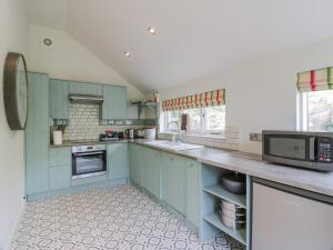 a kitchen with blue cabinets and a microwave at Port Donnel Cottage in Dalbeattie