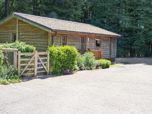 uma cabana de madeira com uma cerca em frente em Ash Lodge em Clatworthy