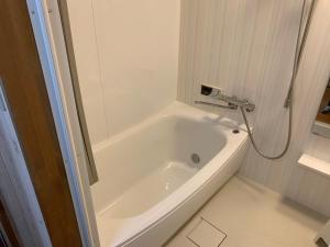 a white bath tub in a bathroom with a shower at Guesthouse Shin in Omihachiman