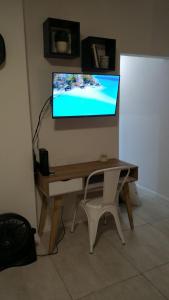 TV en la pared con escritorio y silla en MONOAMBIENTE NORDICO en Mar del Plata