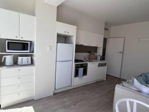 墨爾本的住宿－Modern Beach Oasis in Elwood Village，厨房配有白色橱柜和白色冰箱。
