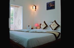 - une chambre avec un lit doté de draps blancs et une fenêtre dans l'établissement Cam Nam Homestay, à Hội An